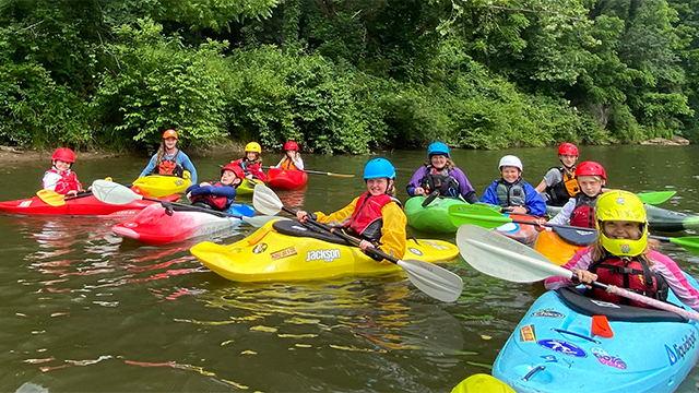 Kids building confidence by paddling whitewater kayaks during one of many fun outdoor activities in north carolina